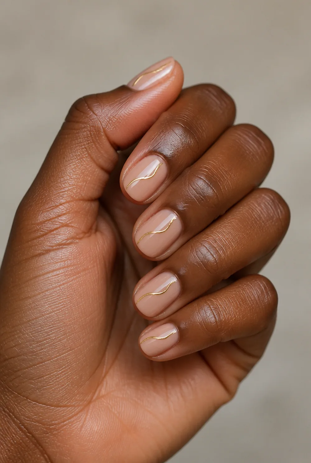 gold swirl nail art on deep brown skin